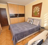 A bedroom in a 3-room apartment with a spacious wardrobe and a floor with a wooden decor.