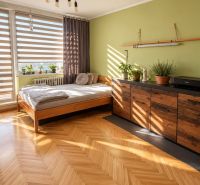 A bedroom in a 3-room apartment with a wooden decor floor and plants.