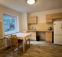 A kitchen in a family house with a wooden decor floor and a large window.
