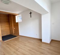 A room in a family house with a wooden decor floor and a cross on the wall.