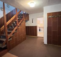 The interior of the family house with a staircase and cladding appears cozy and practically furnished.
