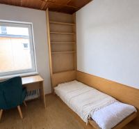 A simple room with a bed, a table, and a chair, floor with wooden decor.