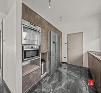 A kitchen in a villa with a marble floor, built-in appliances, and an American refrigerator.