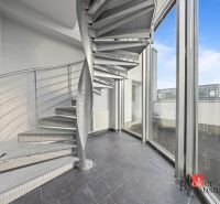 A spiral metal staircase next to large glass windows in the interior of a villa.
