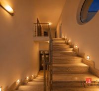 The interior of the villa with a stone staircase and subtle lighting on the walls.