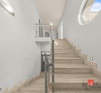 A staircase in a villa with marble steps and stainless steel railing.