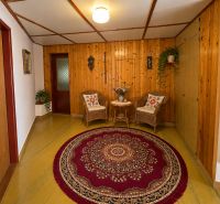In a family house with a wooden decor floor, there is a cozy seating area and a small rug.