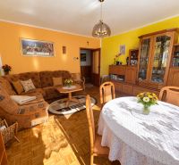 Living room in a family house with a sofa, dining table, and wooden decor flooring.