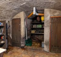 Storage space with supplies in a family house, lined with stones and wooden doors.