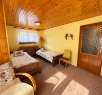 Wooden wall paneling in a room with two beds, Family house.