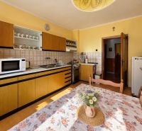 A kitchen with original wooden furniture and a floral tablecloth in a family house.