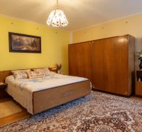A bedroom with yellow walls, carpet, and wood-patterned flooring in a family house.
