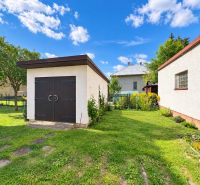 A family house in Liptovské Revúce, a garden with a lawn, wooden doors, blue sky.