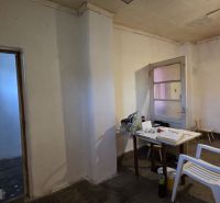 A room in a family house with a plastic chair and a simple table.