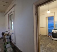 A family house with a kitchen, tiled floor, and a window, entrance to another room.