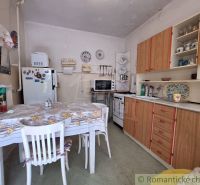 In the kitchen of the family house, there is a table with chairs and a kitchen unit.