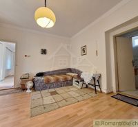 A room with a wooden decor floor, a sofa, and a light in a family house.