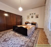 A bedroom in a family house with a wood-patterned floor, a large wardrobe, and curtains.