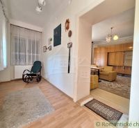 Interior of a family house with a wooden decor floor, rocking chair, and curtains.