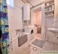 A bathroom in a family house with a bathtub, a sink, a washing machine, and white tiles.