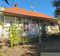 A family house in Moča with a red roof and a garden full of vines.