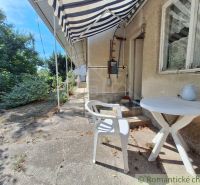 A family house in Moča with garden furniture, an awning, and windows with lace curtains.