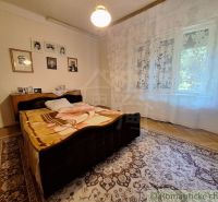 Bedroom in a family house with a bed, curtains, carpet, and wooden decor flooring.