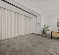 Offices with carpeted surfaces, wooden desks, and plants for decoration.