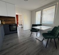 A bright kitchen with a dining table, wooden decor flooring, and an open passage to a room in a 3-room apartment.