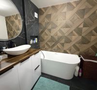 A bathroom in a 3-room apartment with a bold pattern on the wall and a freestanding bathtub.