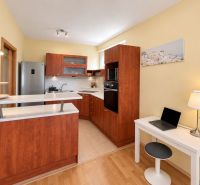 A kitchen with wooden decor in a 3-room apartment, light wall, white countertop.