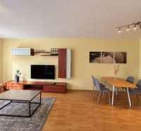 Living room in a 3-room apartment with a wooden decor floor and a dining table.