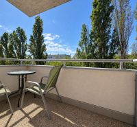 Balcony of a 3-room apartment in Bratislava - Ružinov with a view of trees, table and chairs.