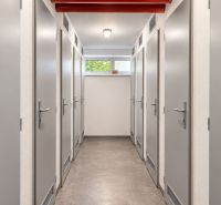 A corridor with multiple doors in a 3-room apartment, light walls and a gray floor.