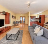 Living room in a 3-room apartment with a wooden decor floor, TV, and sofa.