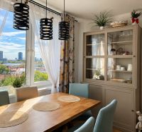 Dining area with a wooden table and a view in a 3-room apartment with plants.