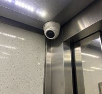 Security camera in the corner of the elevator with lighting and metal cladding.