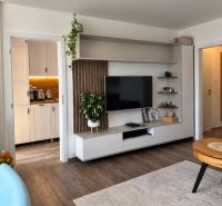 Living room with a TV wall and wooden decor flooring in a three-room apartment.