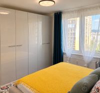 Bedroom in a 3-room apartment with a large wardrobe, yellow blanket, and a view from the window.