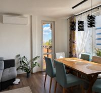 Dining room of a 3-room apartment with a wooden decor floor and a balcony.