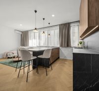 A kitchen space in a 2-room apartment with an island and a wood-patterned floor.