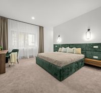 Bedroom in a two-room apartment with a green bed frame and a desk.