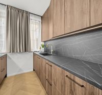 A kitchen with elegant wood-decor cabinets and stylish black countertops.