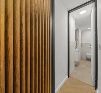 A hallway with a wooden decor floor leads to the bathroom in a 2-room apartment.