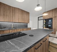 A kitchen in a 2-room apartment with dark cabinets and a marble countertop.