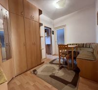 A hallway in a 2-room apartment with built-in wardrobes and a corner seating bench.