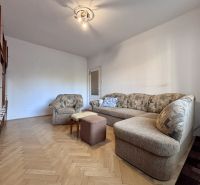 Living room with a sofa, an armchair, and a wooden decor floor in a two-room apartment.