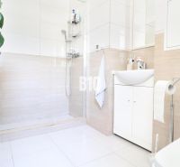A bright bathroom with a shower and white cabinets in a 3-room apartment.