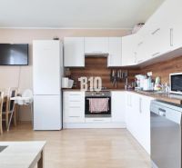 A kitchen in a 3-room apartment with white cabinets and a wooden decor floor.