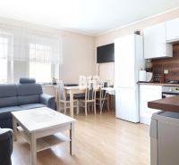Living room in a three-room apartment with a wooden decor floor and light furniture.